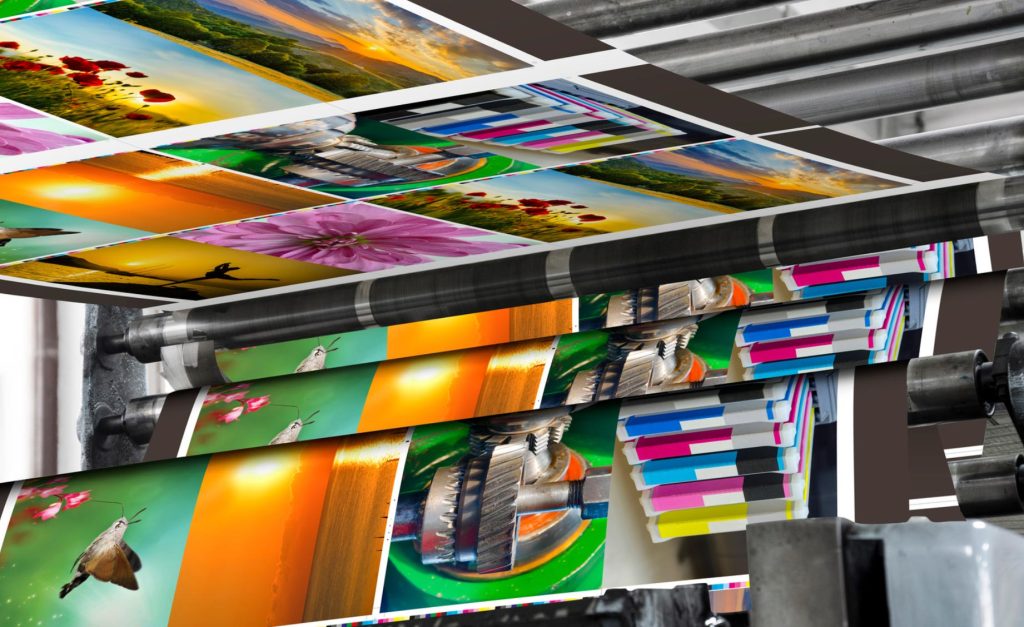 Sheets of colorful photographs being printed on an industrial printer.