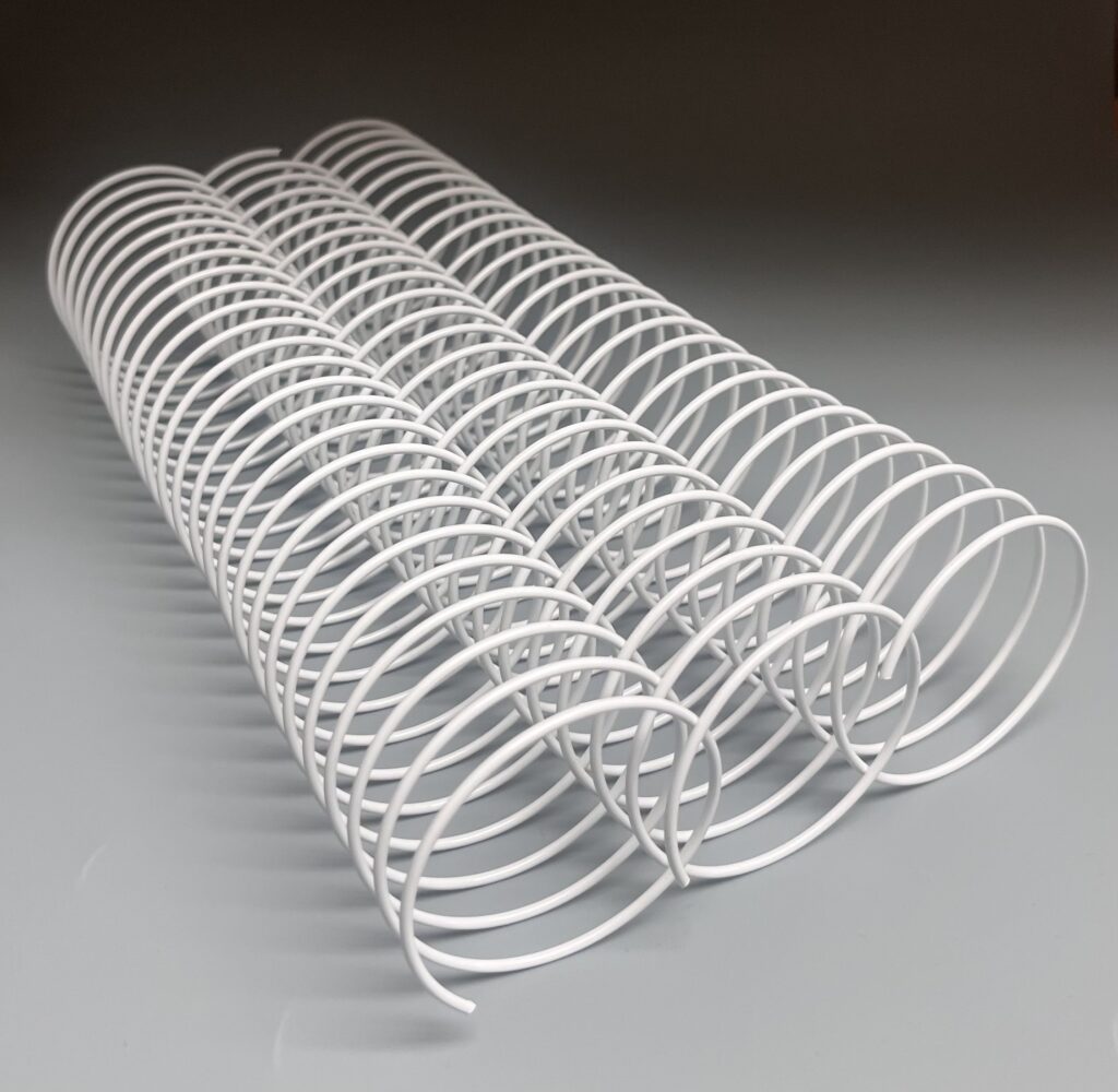 A 2+1/8" x10" #2.5 White Wire Spiral (1 Piece) laying across a gray surface.