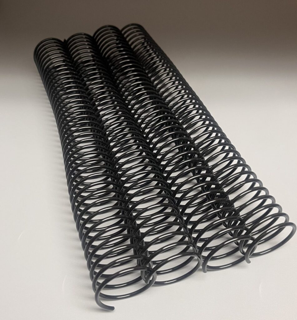 Three black plastic spiral notebook bindings arranged parallel on a light background.