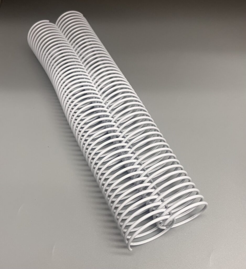 Two white wire binding coils lying side by side on a gray surface.