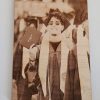 A graduate in cap and gown smiles, holding a diploma with a peace sign at a graduation ceremony, celebrating achievements that could be commemorated with personalized gifts from Laser Engraving Services.