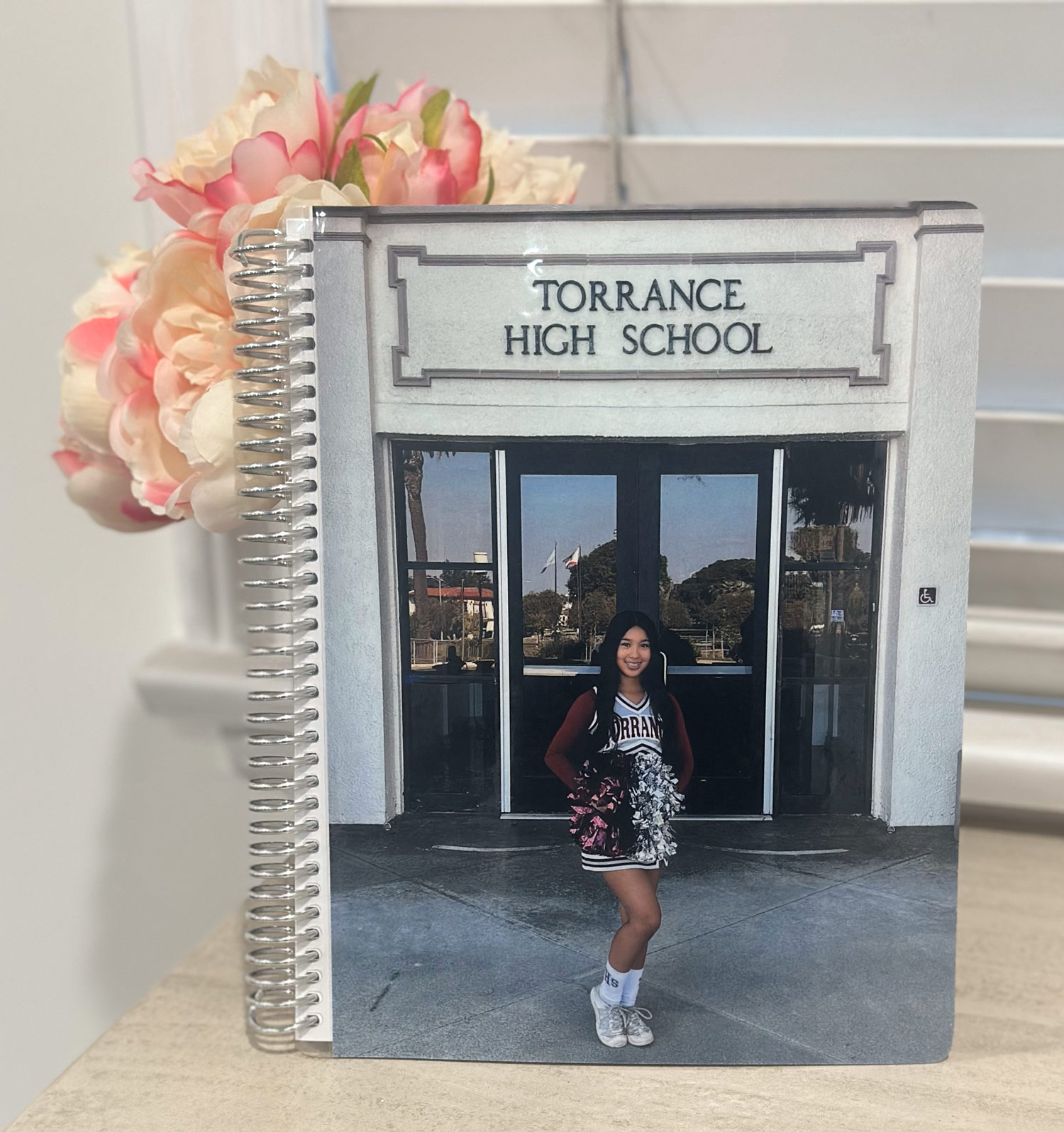 A Custom Notebook featuring a personalized cover with a photo of a cheerleader in front of Torrance High School.