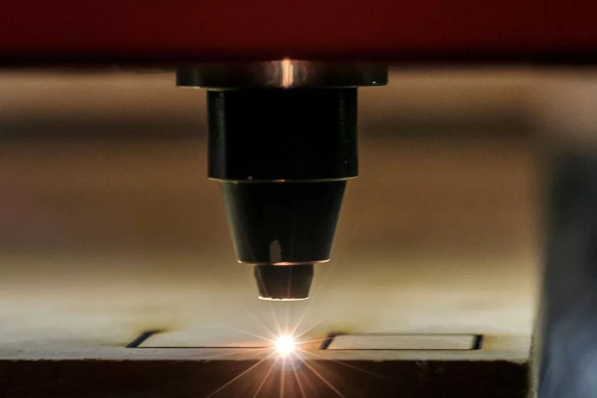 Close-up of a laser cutting machine in action, emitting a bright light as it cuts through a material.