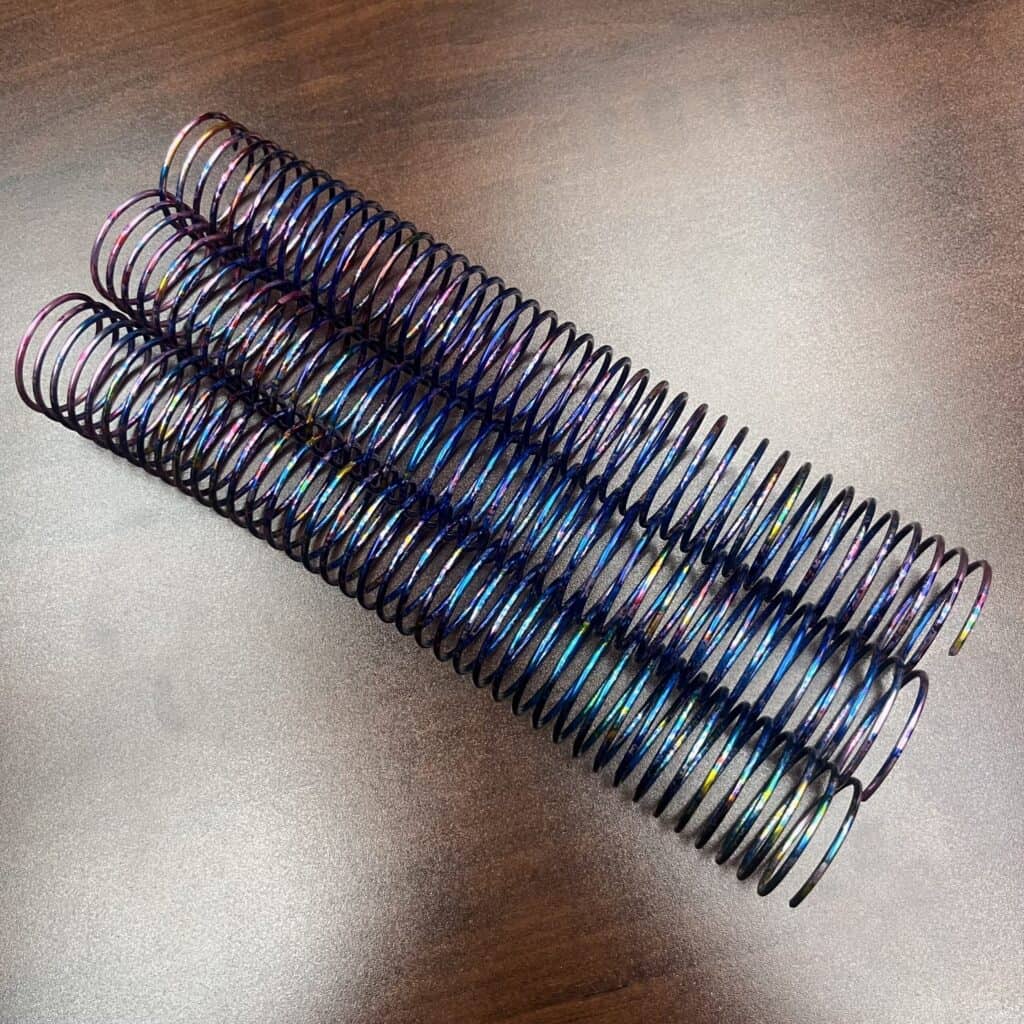 A 1+1/4” x10” #4 Burst Rainbow Spiral is placed on a brown wooden surface.