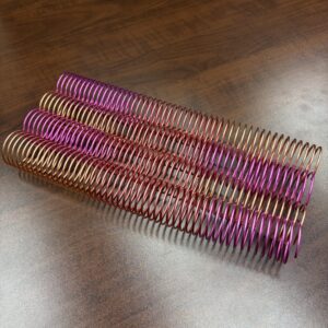A 1 Piece of 1+1/2″ x12″ #4 Petunia Multicolor Spiral is displayed on a wooden surface.