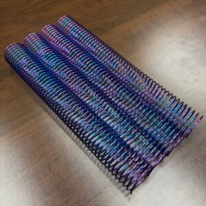 A 1+1/2″ x12″ #4 Purple Burst Multicolor Spiral lies on a wooden surface.